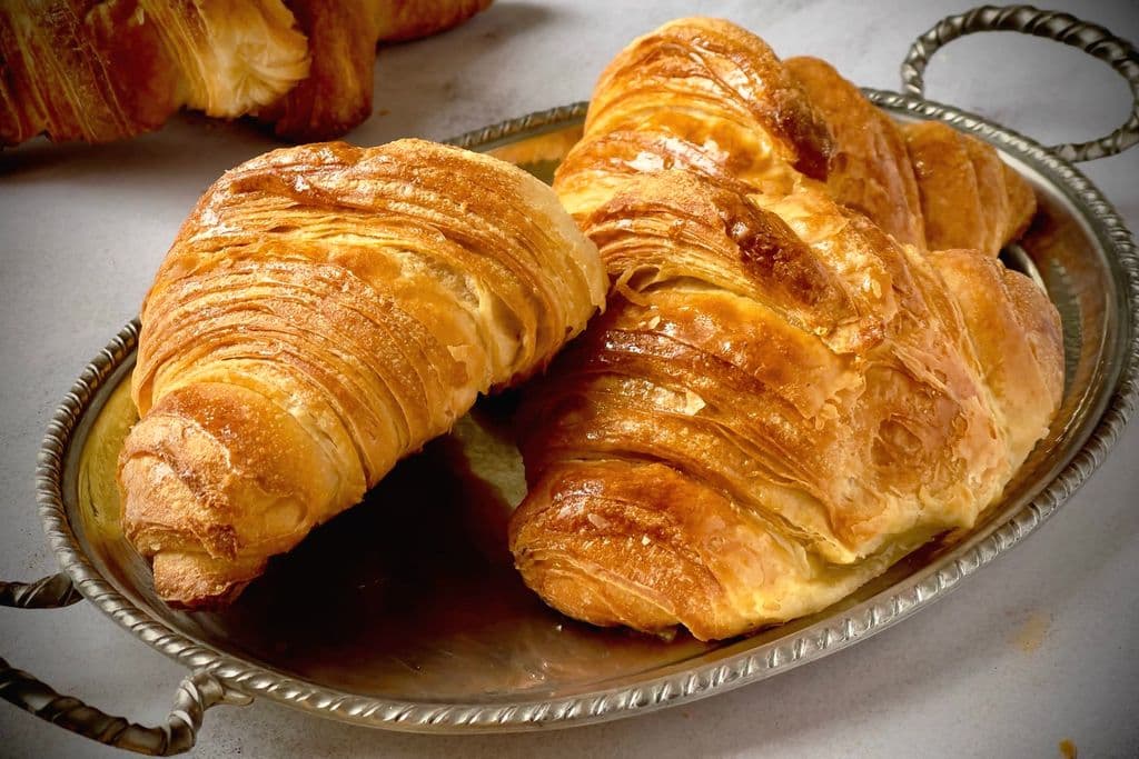 Golden French croissants on a tray, by Jana Ohajdova