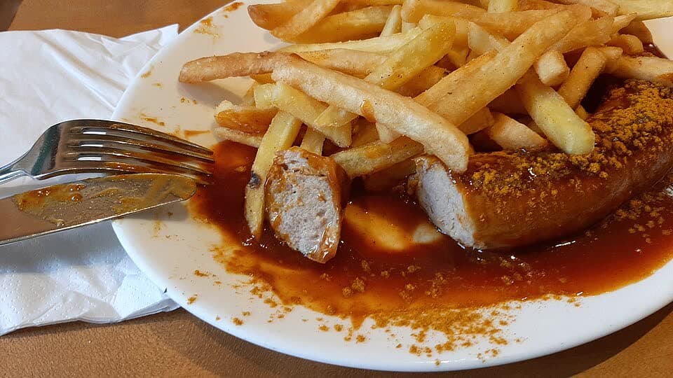 Currywurst with sliced sausage, curry sauce, and fries
