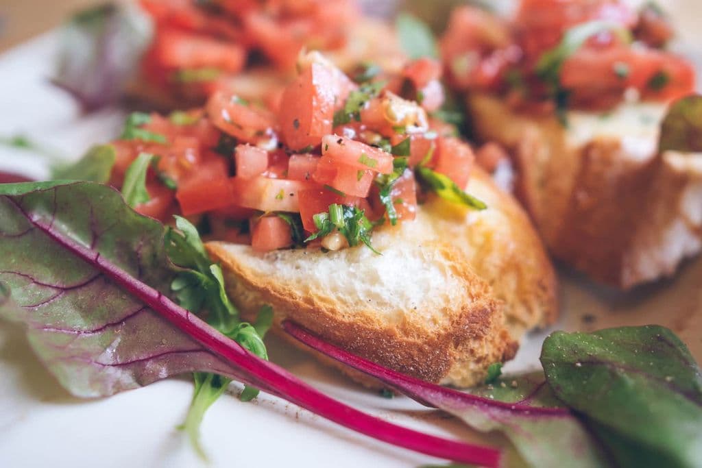 Fresh bruschetta topped with tomatoes and herbs, by jamie patterson