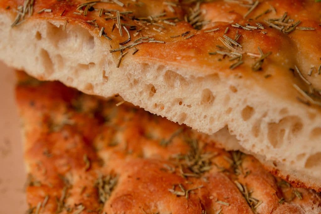 Freshly baked focaccia bread topped with herbs, by Natalia Olivera