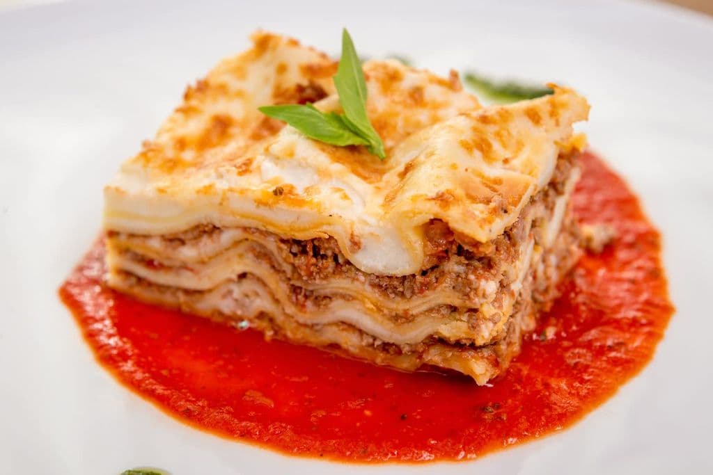 Homemade lasagna topped with fresh basil, by Ioan Bilac