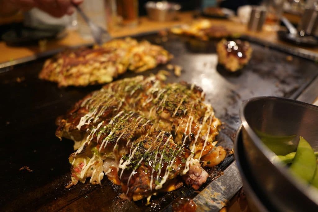 Okonomiyaki cooking on a hot plate, by Yosuke Ota