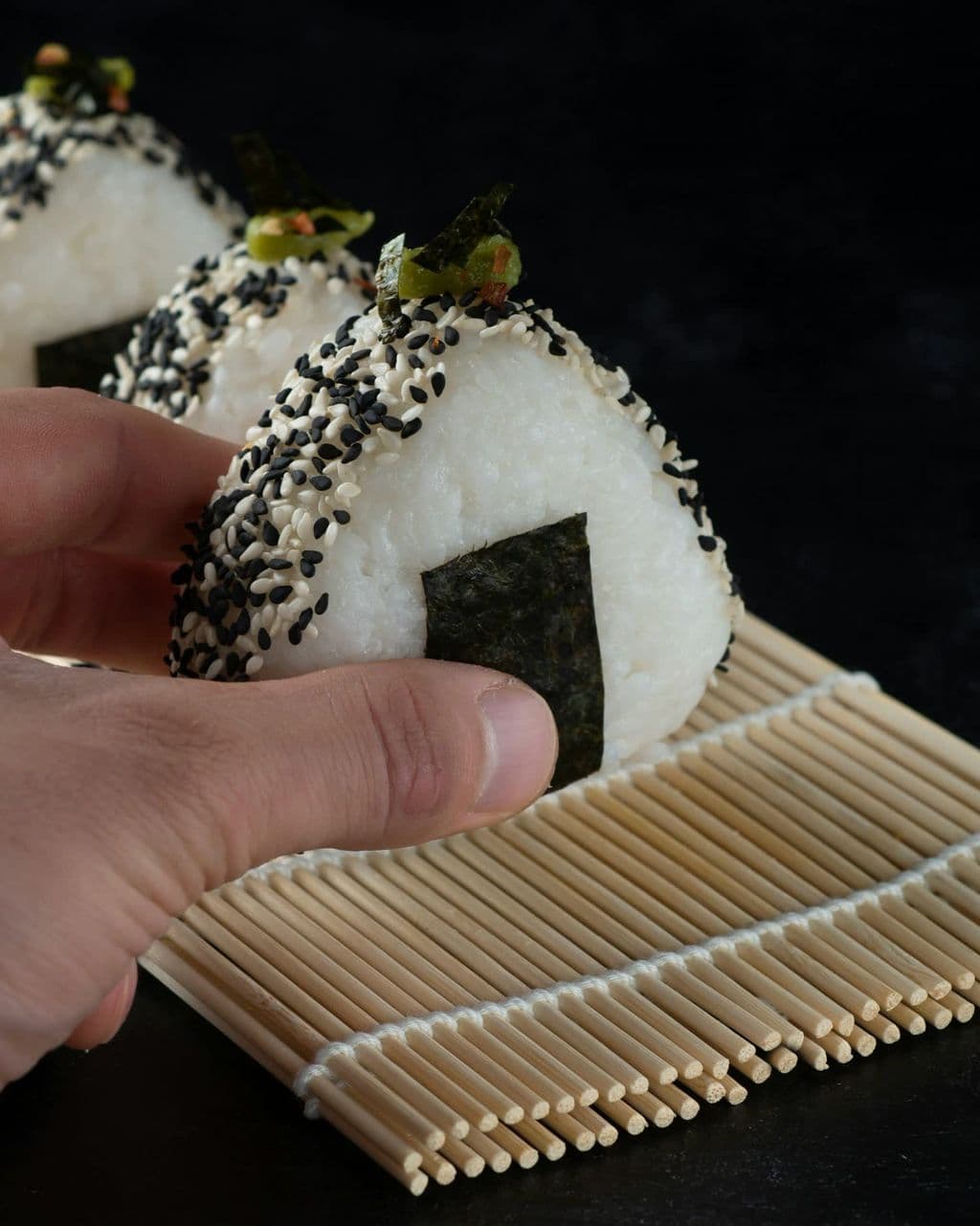 Person holding an onigiri rice ball, by Max Griss