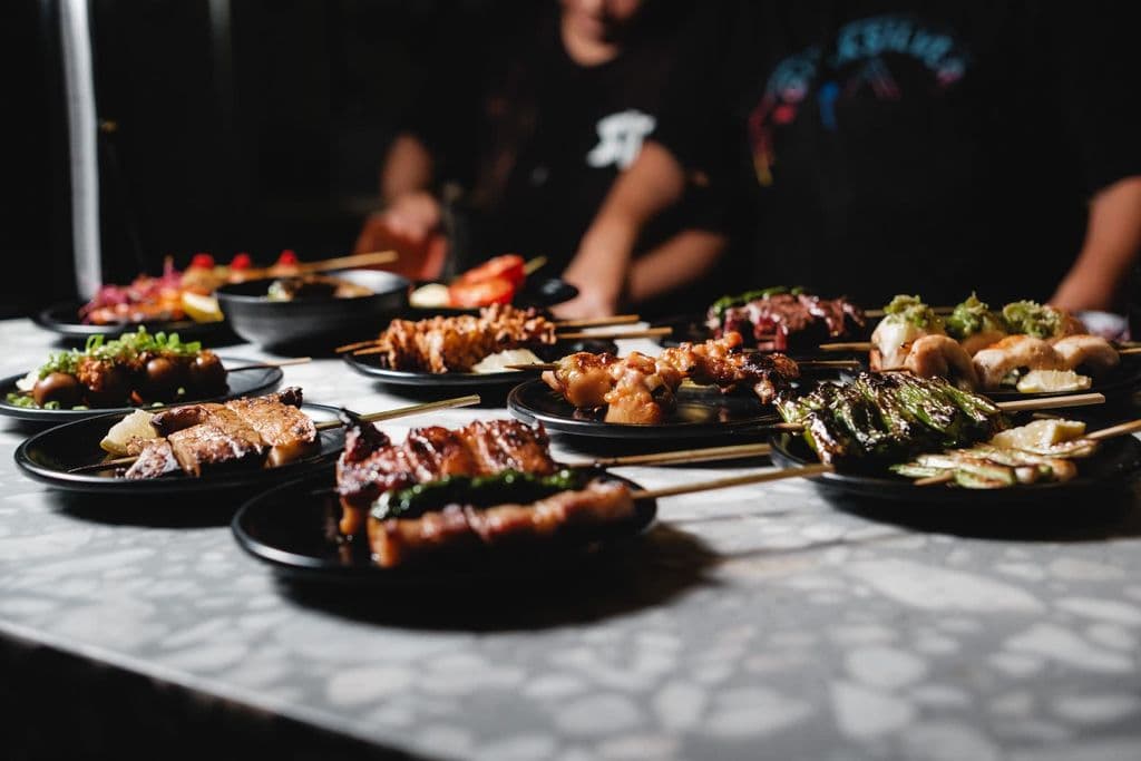 Japanese yakitori skewers on dark plates, by Airam Dato-on