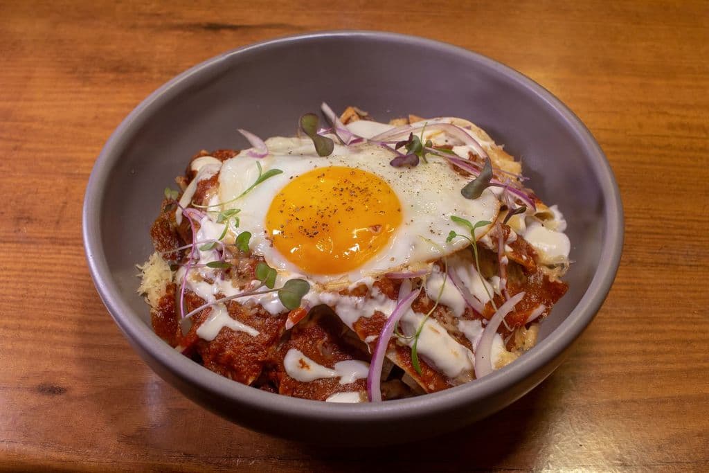 Chilaquiles with salsa and egg in a bowl, by 23 Audiovisual