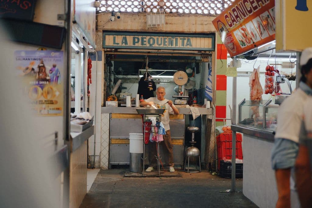 Food vendor at La Pequeñita market stall in Mexico, by Allan González