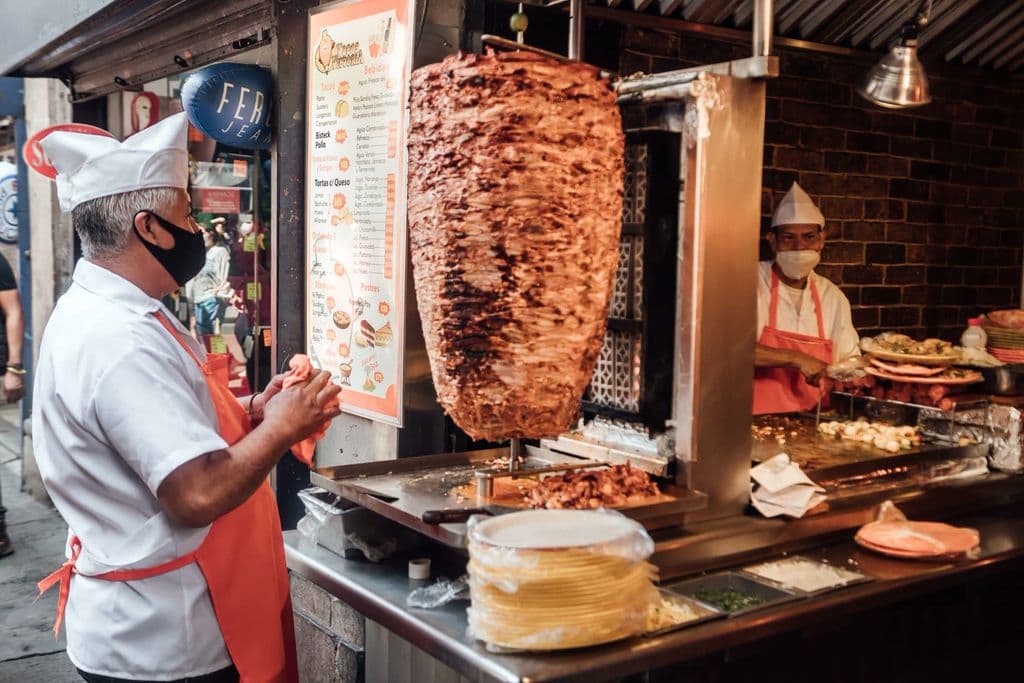 Taco vendor serving al pastor in Mexico City, by Miguel González