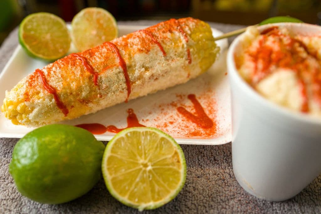 Mexican elote with cheese, chile, and lime, by J E
