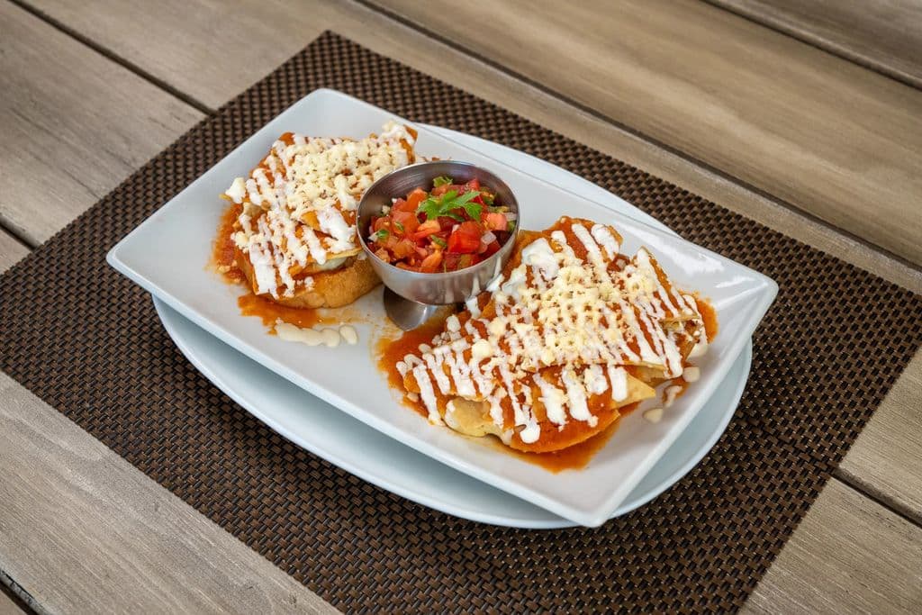 Mexican sopes topped with cheese and salsa, by Allan González