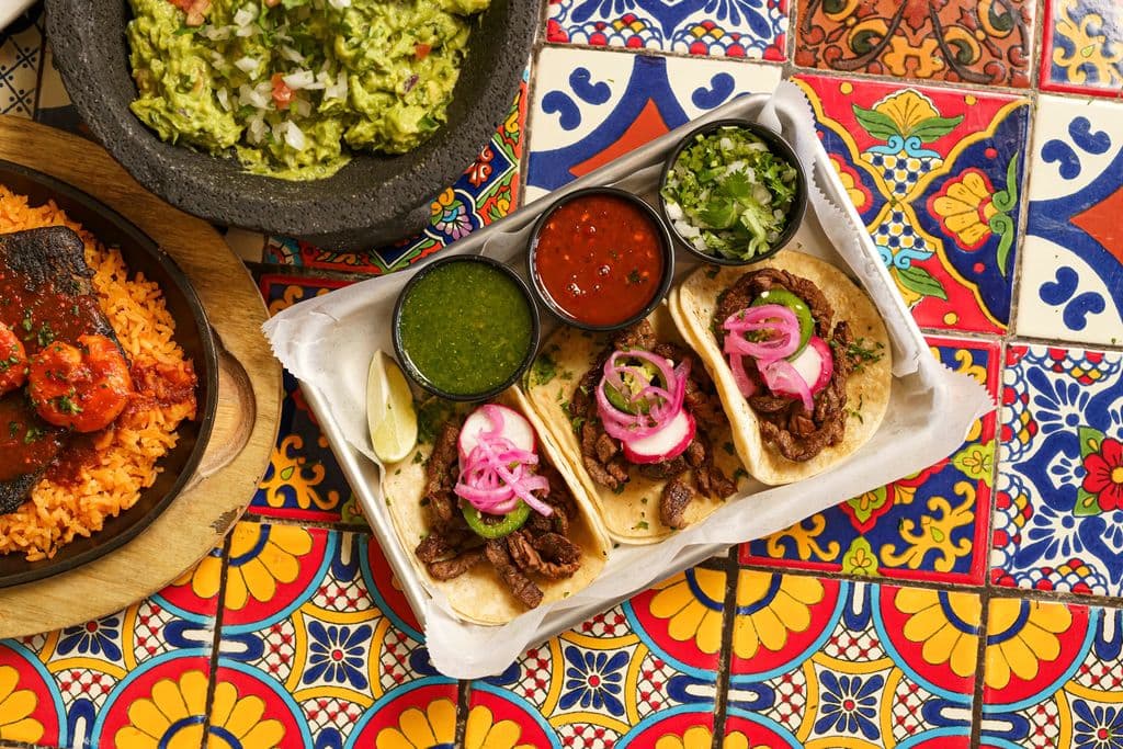 Tacos with colorful salsas and guacamole on a Mexican table, by Hybrid Storytellers