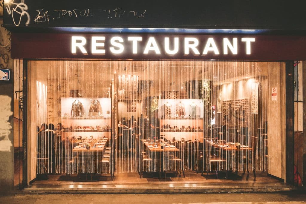 Warmly lit restaurant exterior on a Milan street, by Enrico Frascati