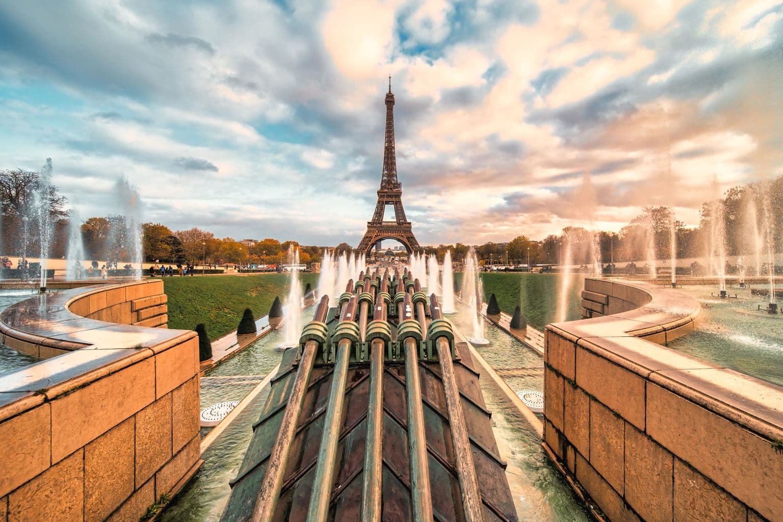 The Eiffel Tower stands majestically amidst the fountain display during a beautiful sunset in Paris, by Masood Aslami