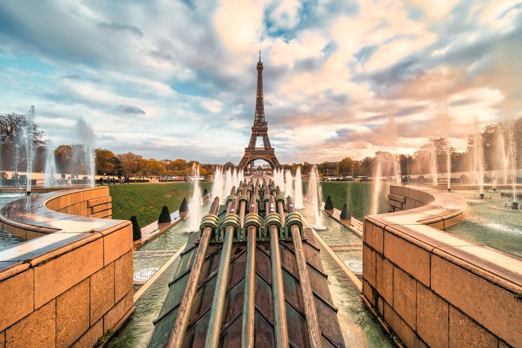 The Eiffel Tower stands majestically amidst the fountain display during a beautiful sunset in Paris, by Masood Aslami