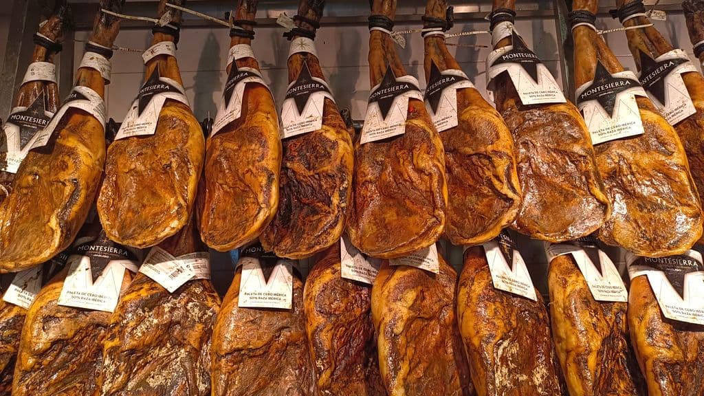 Hanging Jamón Ibérico hams in a traditional setting, by Anatolii Maks