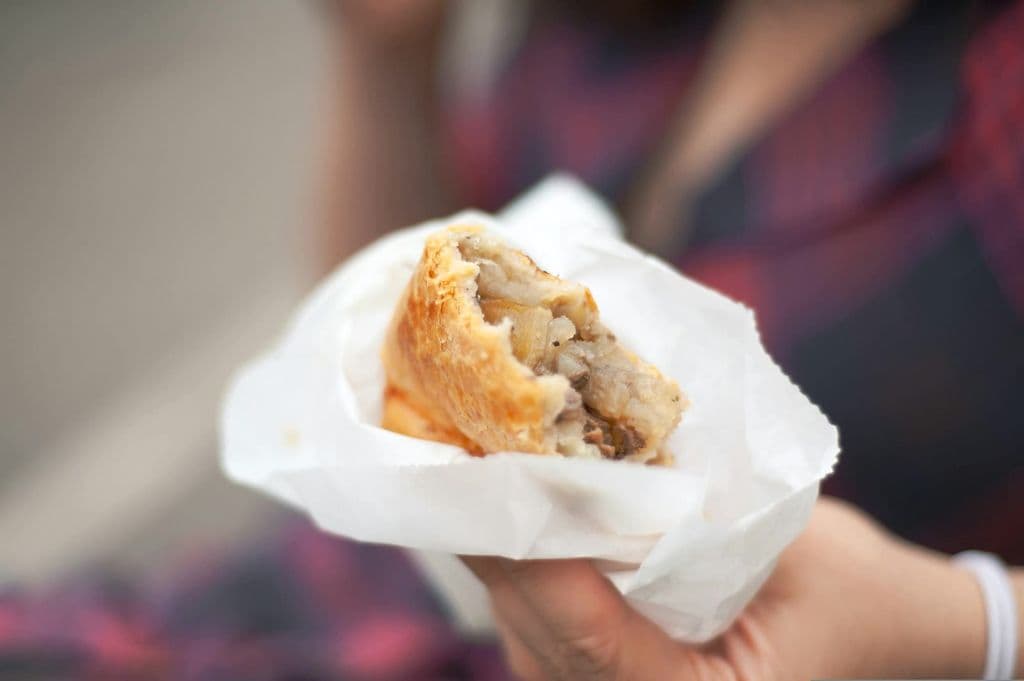 Handheld savory pasty with a visible filling, by Harry Grout